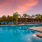 Poolside area with reclining chairs, palm trees, and a sunset